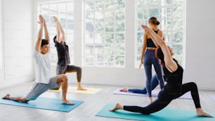 Jovens asiáticos atraentes que praticam aulas de yoga com instrutor. Grupo asiático de mulheres que exercem um estilo de vida saudável no estúdio de fitness. Atividade esportiva, ginástica ou aula de dança de balé.