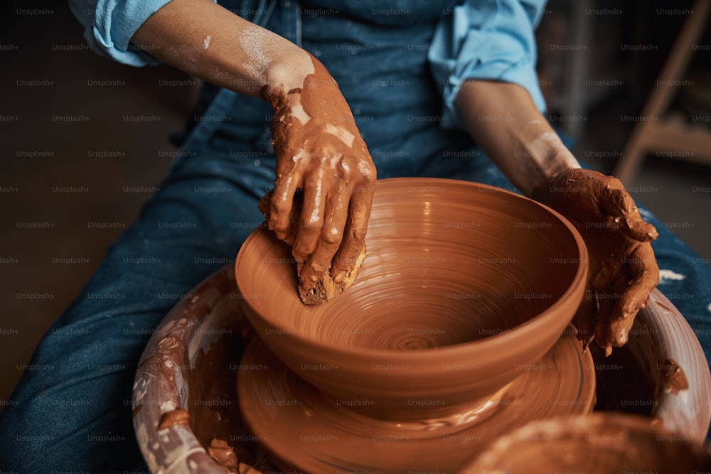 Imagem de vista frontal de perto do processo de fabricação e modelagem da tigela de cerâmica na roda de cerâmica no estúdio de arte