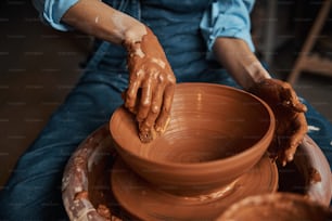 Close up front view image of process manufacturing and modeling ceramic bowl on pottery wheel in art studio