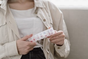 Concepto de atención médica, tratamiento y medicamentos. Vista recortada de una mujer joven sostiene una caja organizadora de plástico con píldoras en las manos. Paciente enferma se queda en casa, toma suplementos recetados y vitaminas