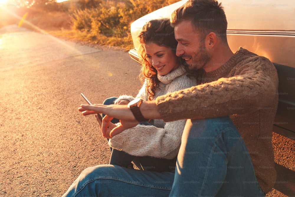 도로 여행에서 아름다운 커플, 그들은 운전에서 휴식을 취하고 태블릿에서 방향을 찾고 있습니다.