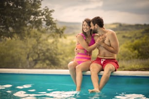 プールに座って一緒に楽しんでいる幸せな笑顔のカップル。