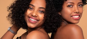 Two beautiful afro women posing together smiling, looking at camera.  A lot of copy space. Real people emotions, skin care and makeup.