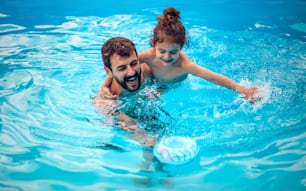 Father and son playing together in the swimming pool.