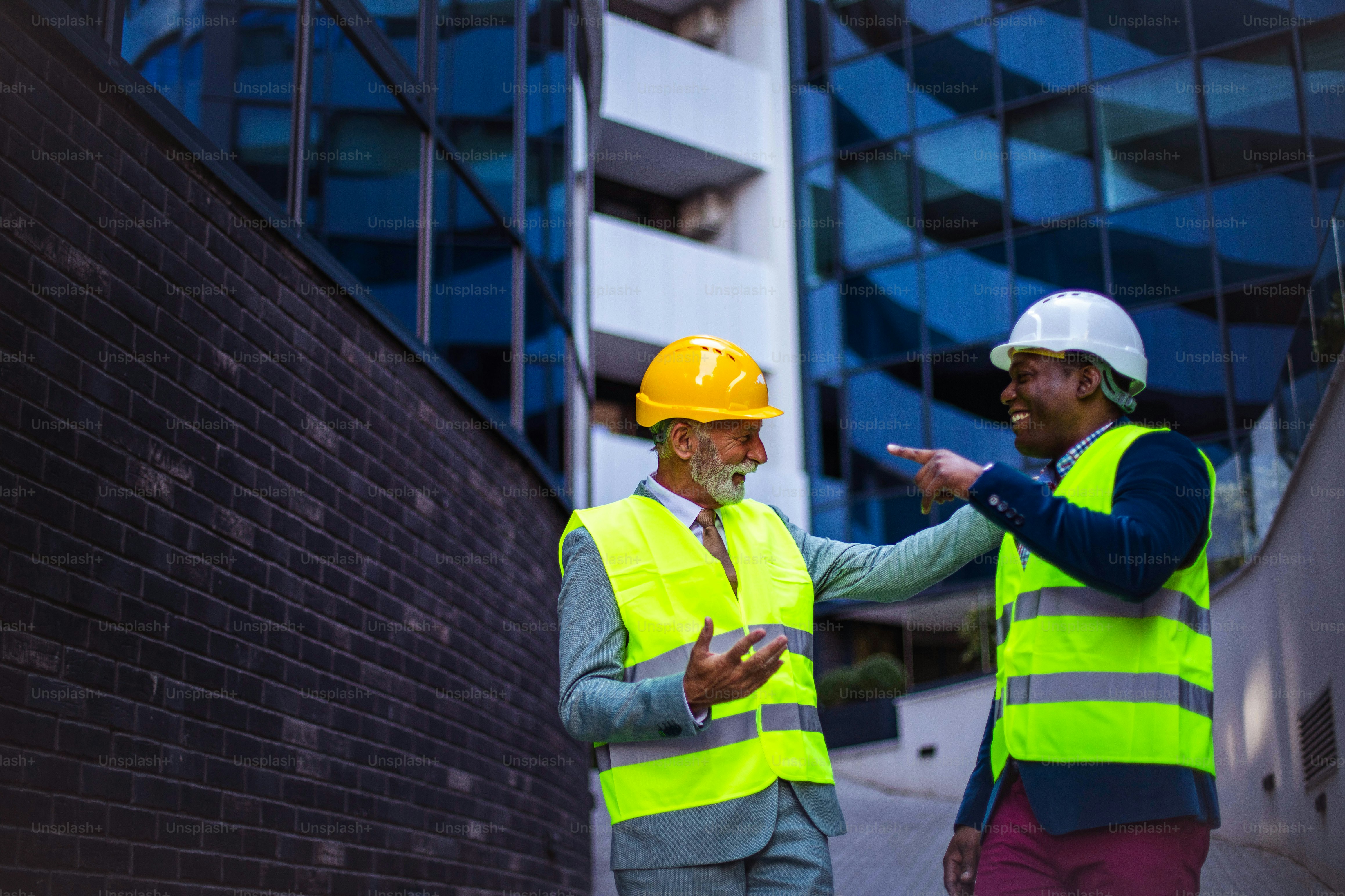 Reifer Ingenieur bespricht die Struktur des Gebäudes mit Architektenkollegen auf der Baustelle. Geschäftsleute im Gespräch.