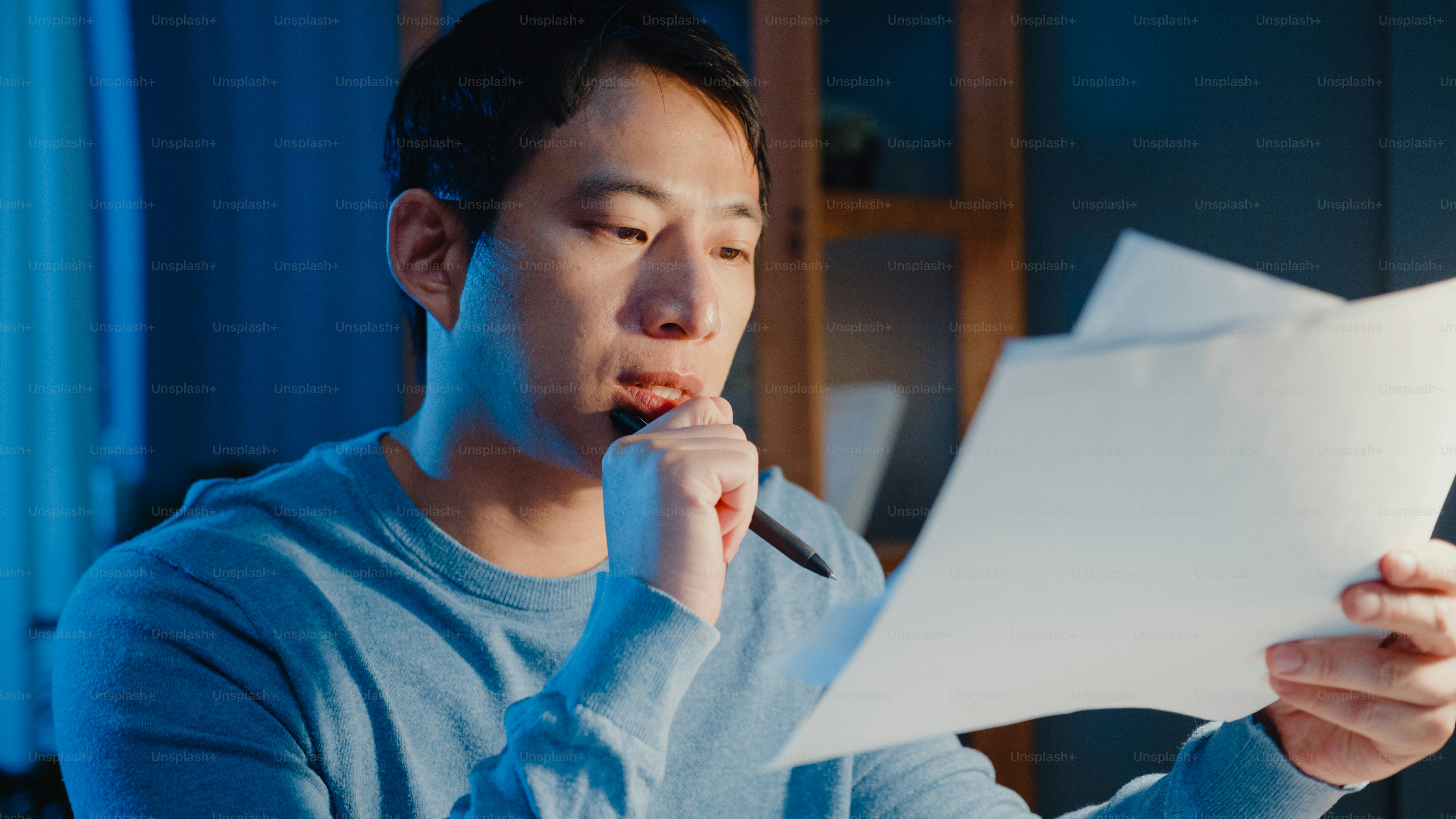 Man reading documents in blue sweater - Photo on Unsplash+