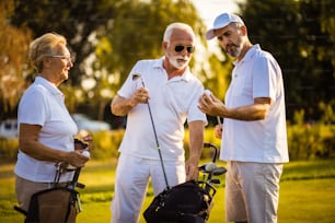 Des amis plus âgés sur le terrain de golf parlent.