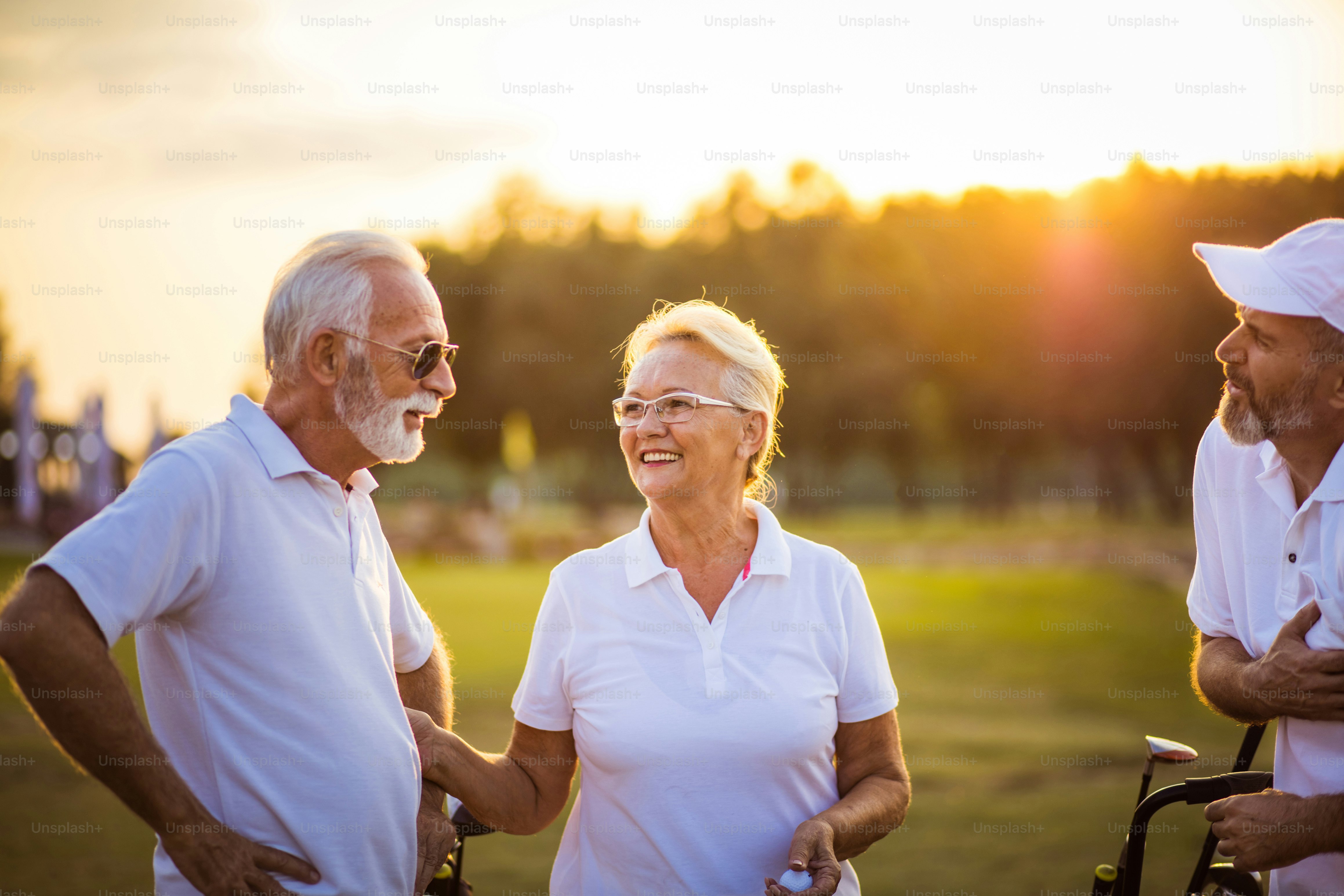 ゴルフ場で話す3人の先輩ゴルファー。