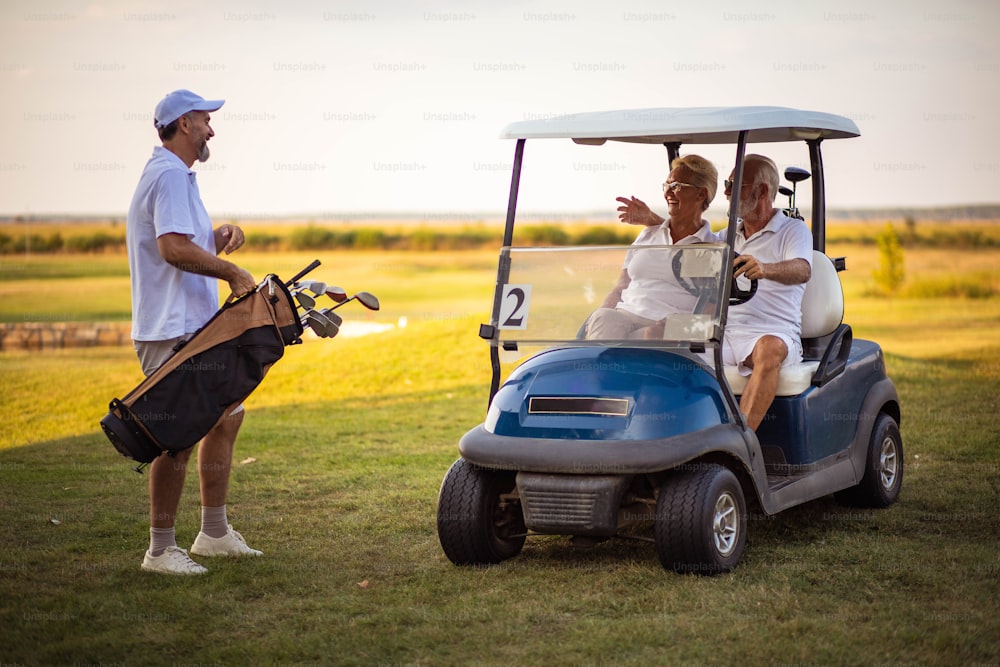 Three seniors golfers. Man and woman in golf car.