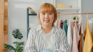 Portrait of young Asia lady fashion designer feeling happy smile, arms crossed and looking to camera while working clothing store in home office. Small business owner, online market delivery concept.