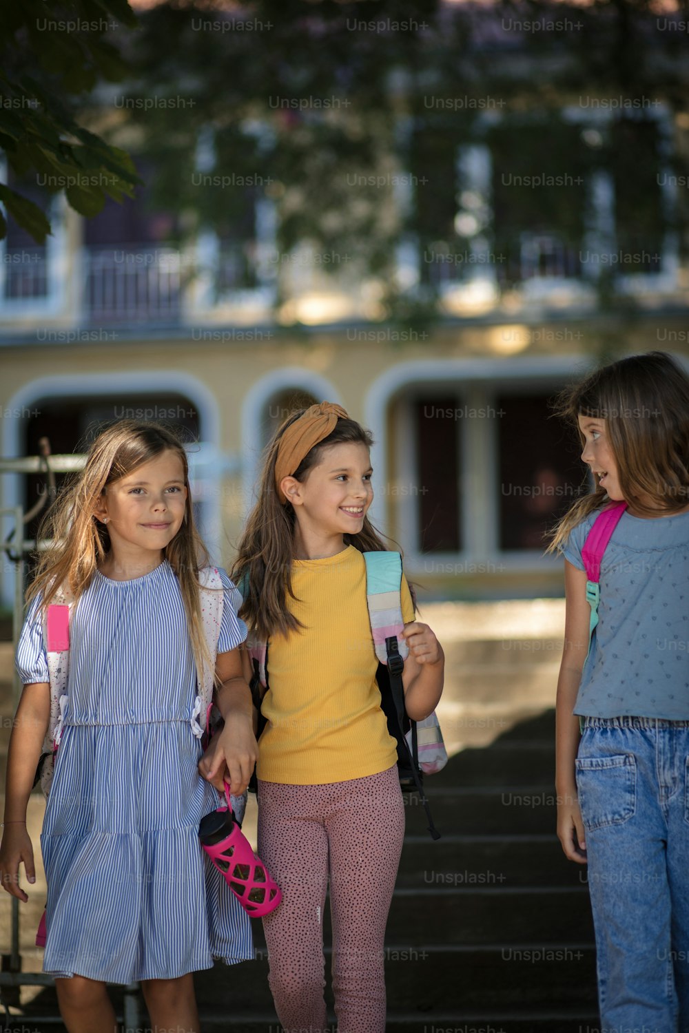 Three little smiling girls going home after school.