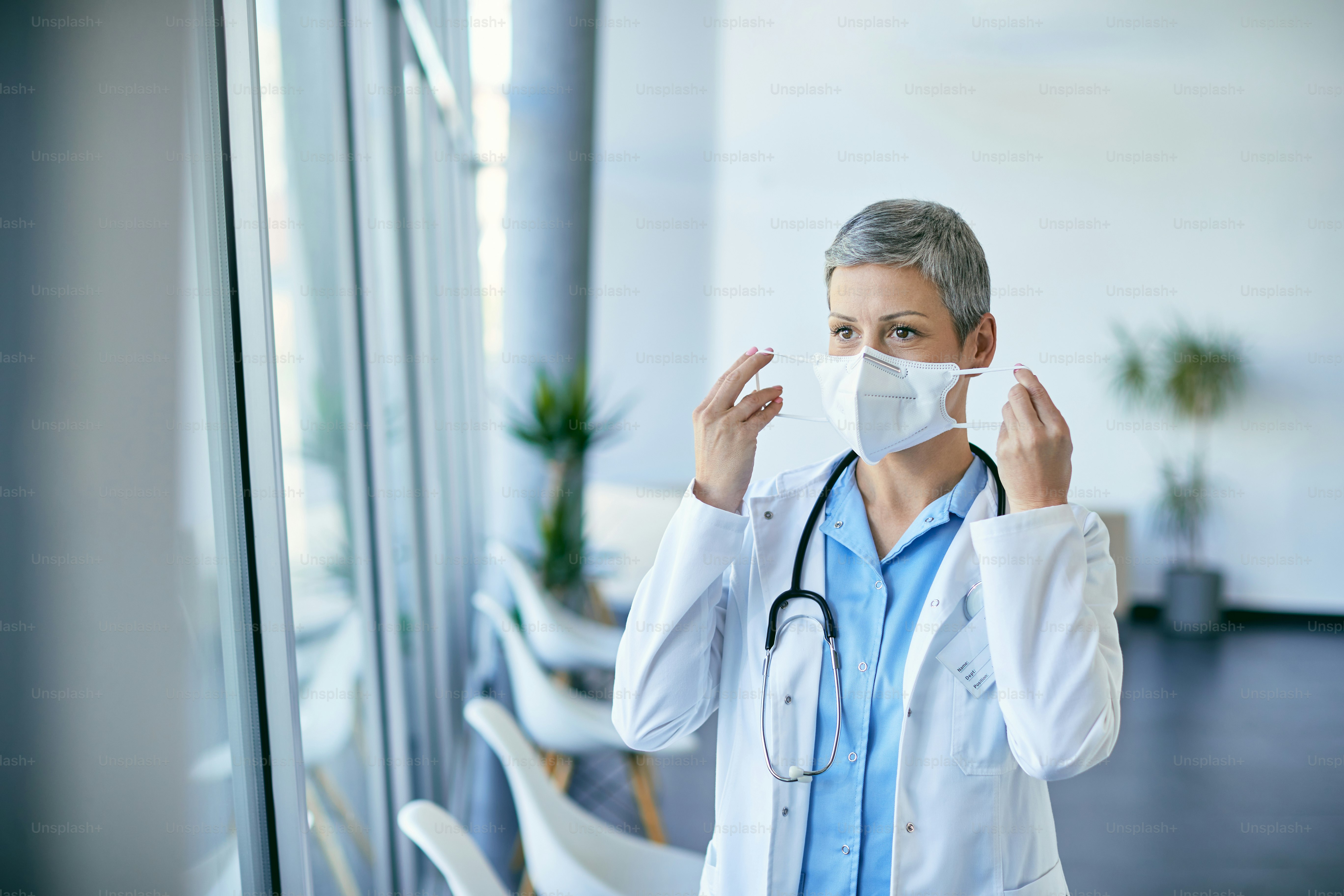Female doctor putting on face mask while working in the hospital during COVID-19 pandemic.