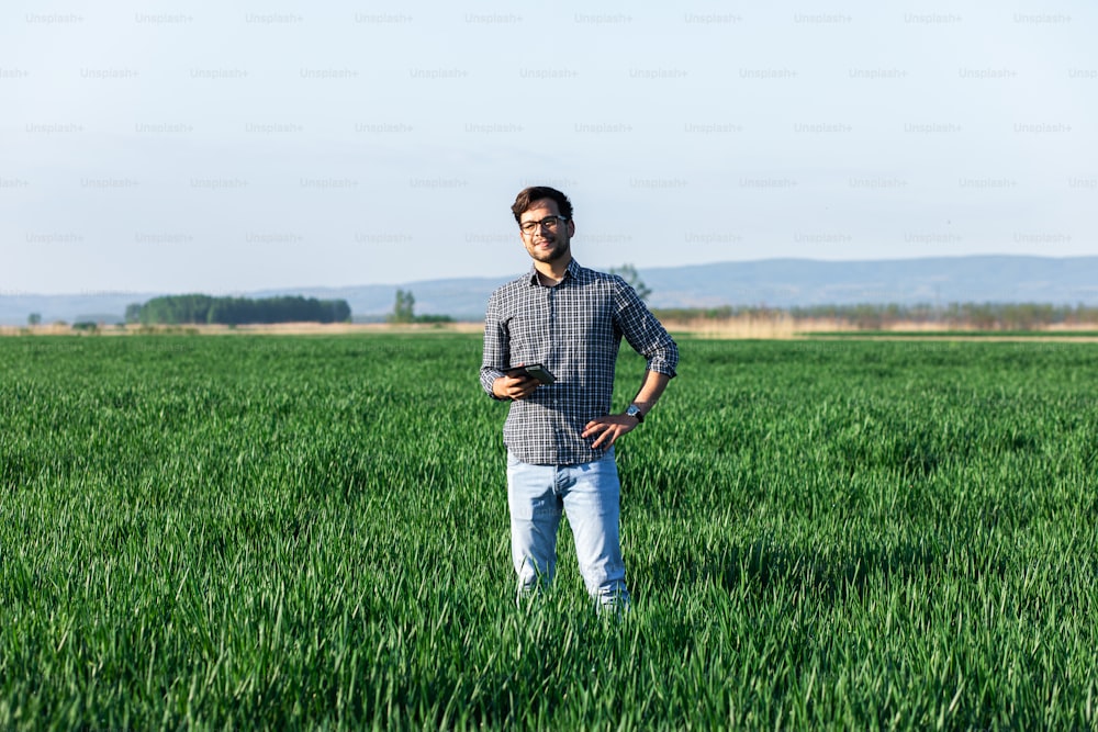 Young farmer standing in young wheat fields.