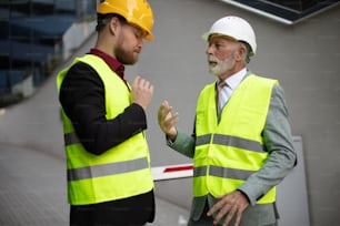 Ingeniero maduro discutiendo la estructura del edificio con un colega arquitecto en el sitio de construcción.