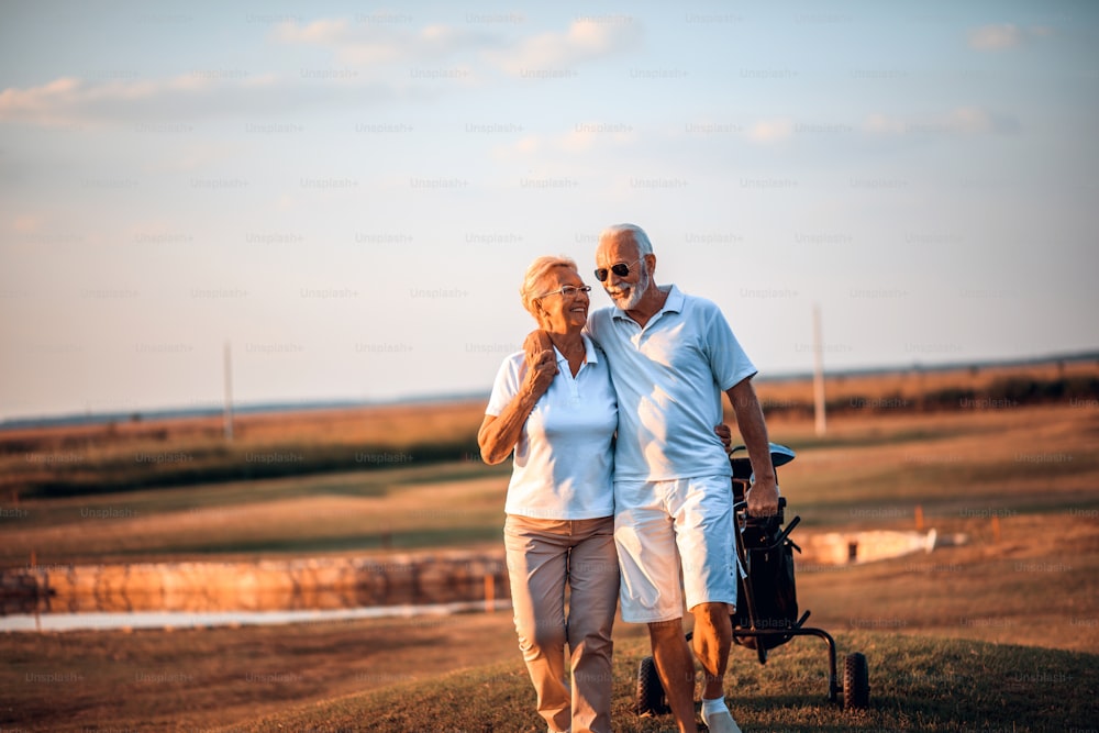 Golfisti anziani che parlano e camminano sul campo da golf.