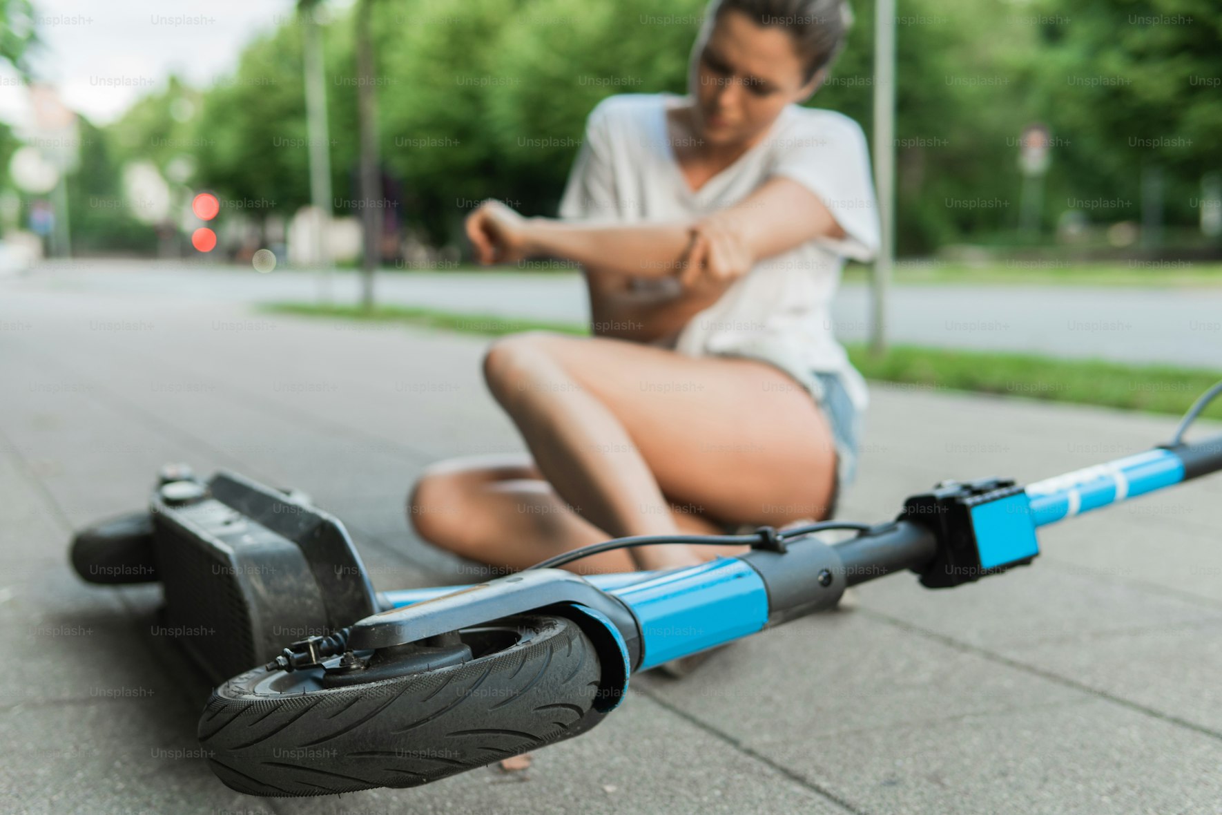 An injured woman lying on ground with a fallen e-scooter beside her