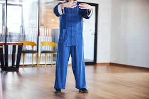 Cropped photo of unrecognized woman in a blue Chinese suit standing with her hands up