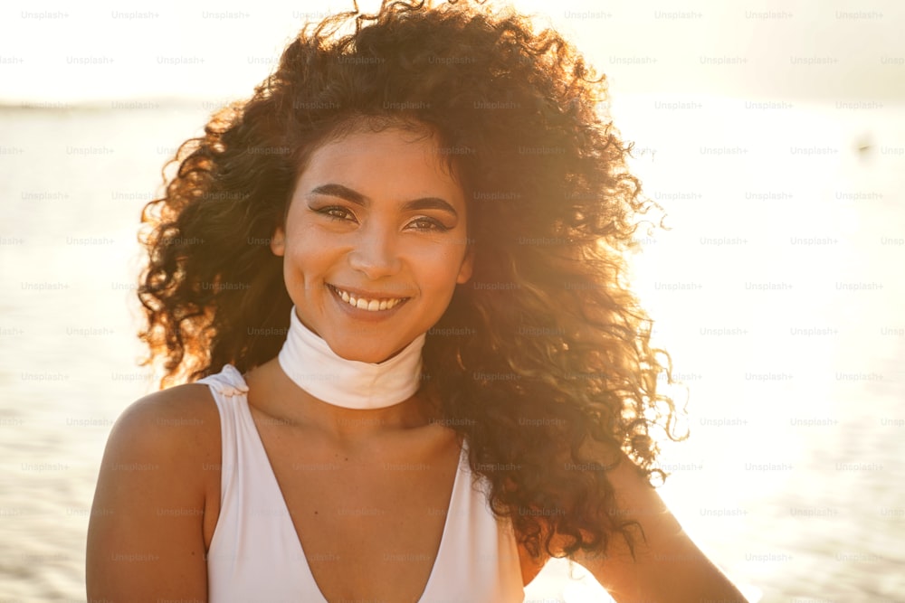 Close up beauty portrait of a happy beautiful colombian woman with afro hairstyle. Girl looking at camera and smiling. Sunset light.