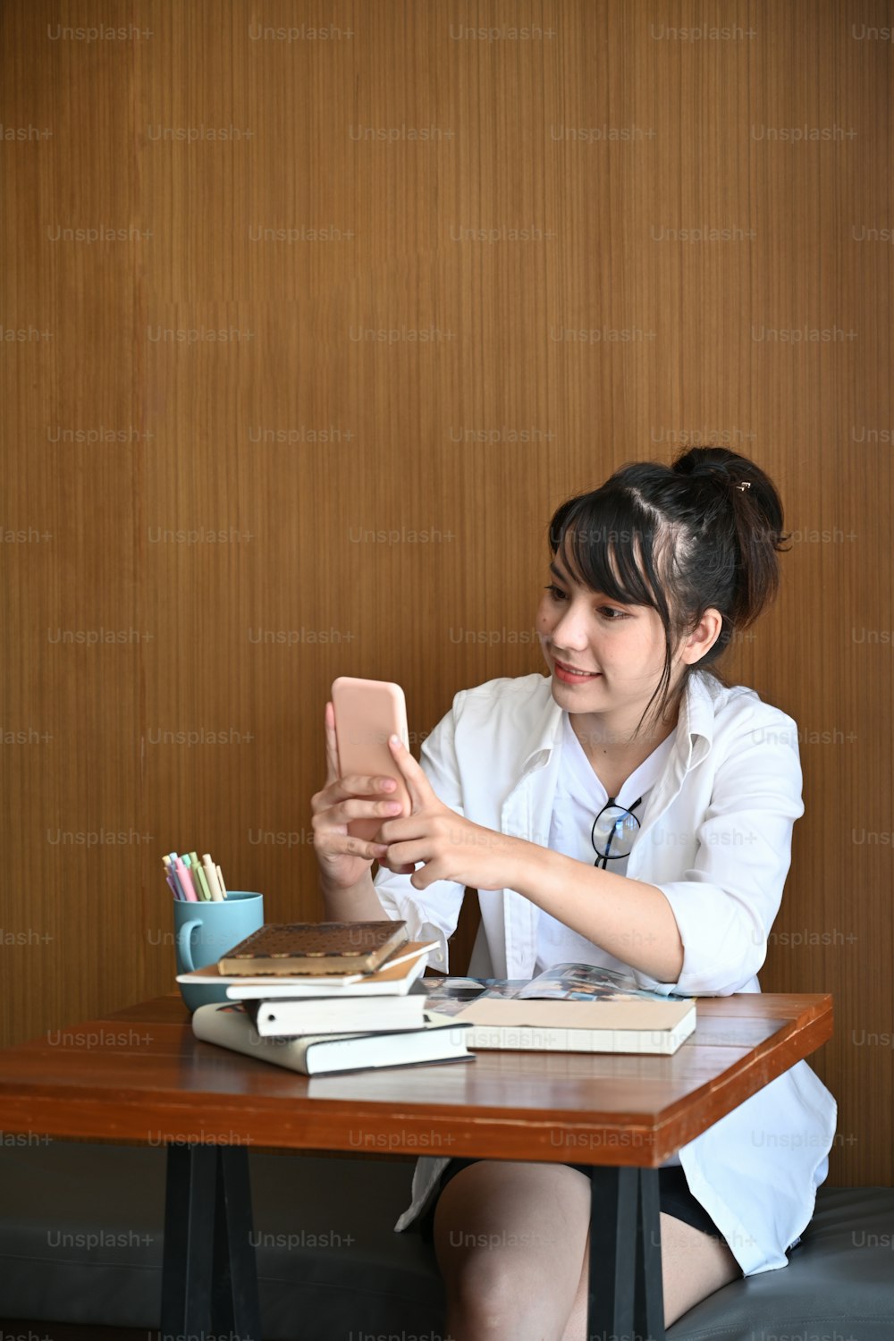 Porträt einer schönen jungen Frau, die im Café sitzt und ihr Handy benutzt.