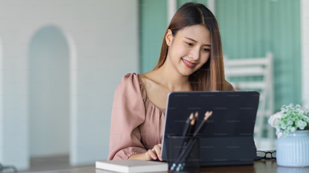 Portrait of female office worker working with digital tablet and stationery on portable workspace