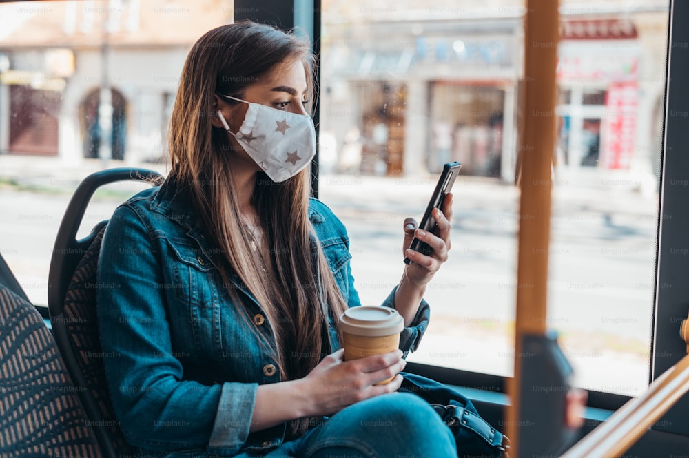 Woman wearing protective mask while riding a bus and sitting on a distance from other passengers due to covid19 pandemic