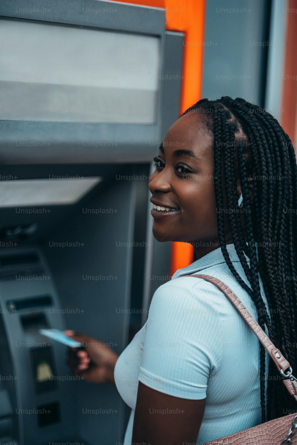 Mujer afroamericana alegre usando tarjeta de crédito y retirando efectivo en el cajero automático