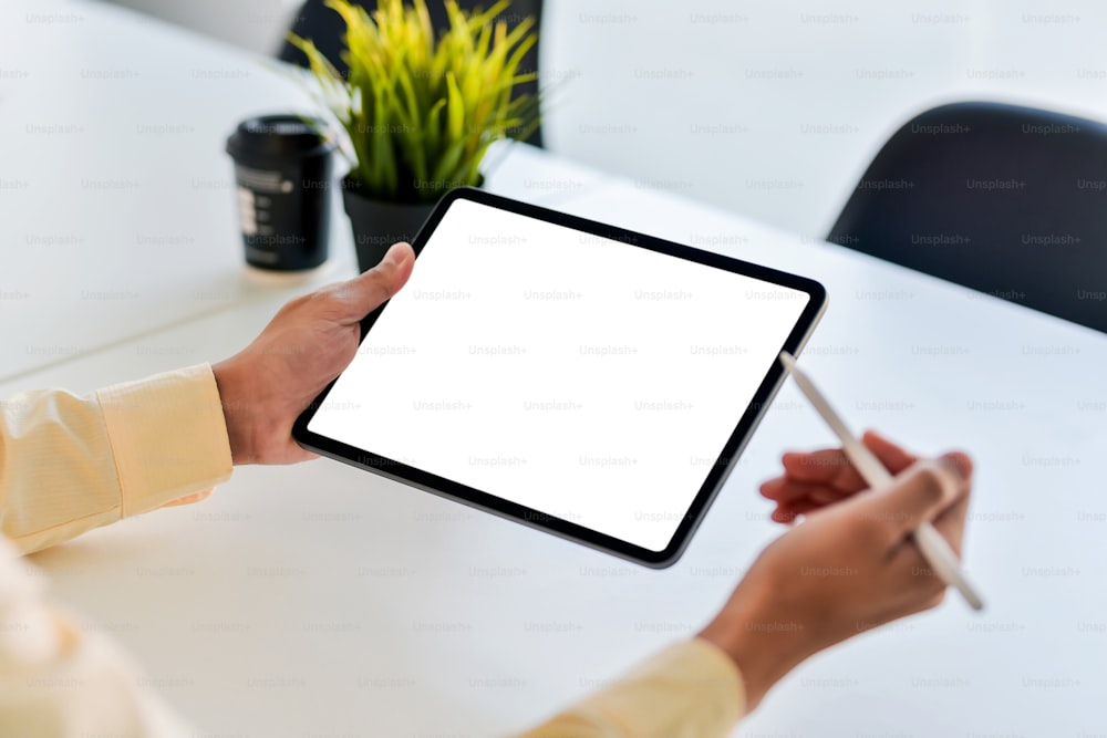 Primer plano de un hombre de negocios sosteniendo una pantalla blanca en blanco de una tableta digital en la oficina. Maqueta.