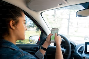 Retrato de uma jovem mulher usando o sistema de navegação gps em seu telefone celular enquanto dirigia seu carro. Conceito de transporte e navegação.