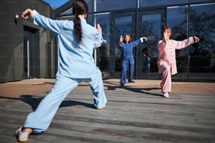Frauen in schöner chinesischer Kleidung an der Bewegungsmeditation während ihrer Qigong-Praxis beteiligt