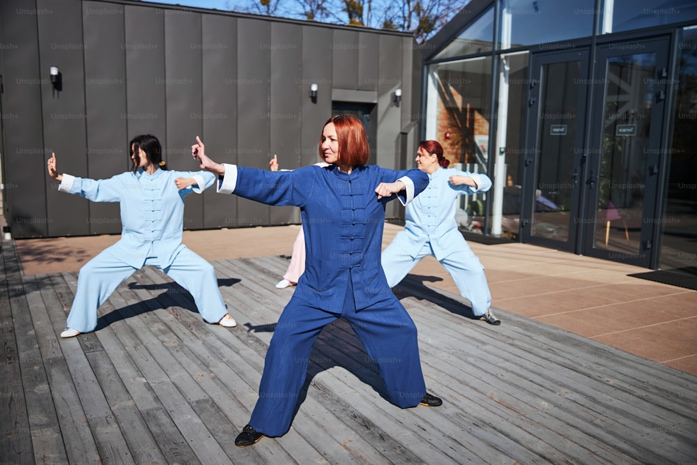 Beautiful young women wearing colorful Chinese clothes practicing tai chi outdoors on a sunny day