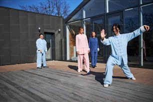 Master of traditional Chinese martial arts demonstrating her movements to the students on a terrace