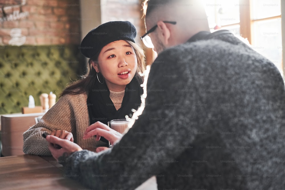 Multirassisches Paar spricht im Café. Asiatisches Mädchen mit ihrem kaukasischen Freund.