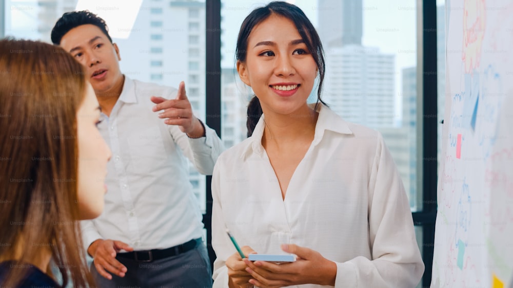 Geschäftsleute und Geschäftsfrauen aus Asien treffen sich mit Brainstorming-Ideen Durchführung von Geschäftspräsentationen Projektkollegen, die zusammenarbeiten Plan Erfolgsstrategie genießen Teamarbeit in kleinen modernen Büros.