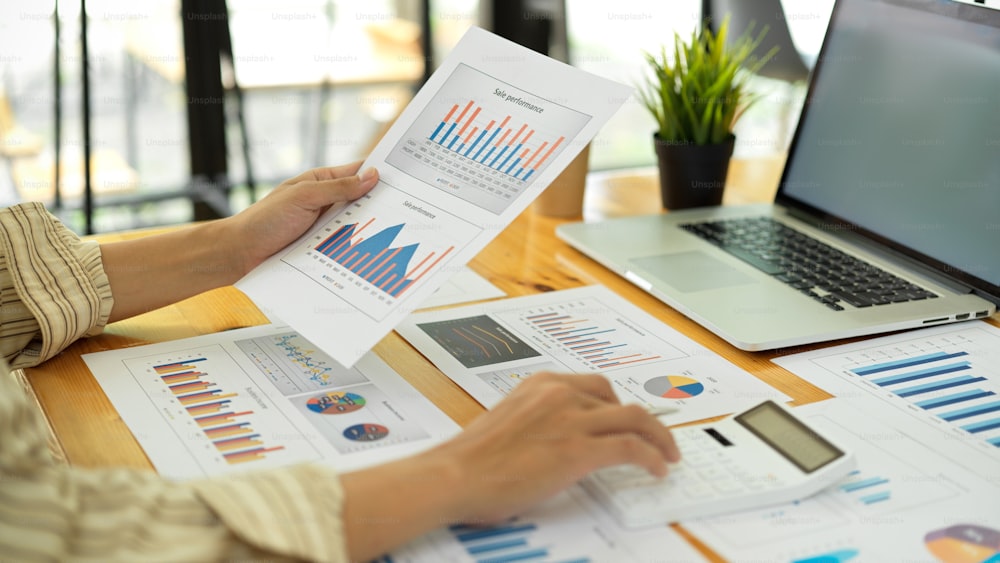 Side view of businessperson hands working with calculator and business paperwork on office desk