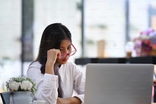 Empresária cansada sentada na frente de seu laptop e sentindo estresse do trabalho.