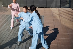 Experienced tai chi master standing near her student and gently helping her to coordinate the movements