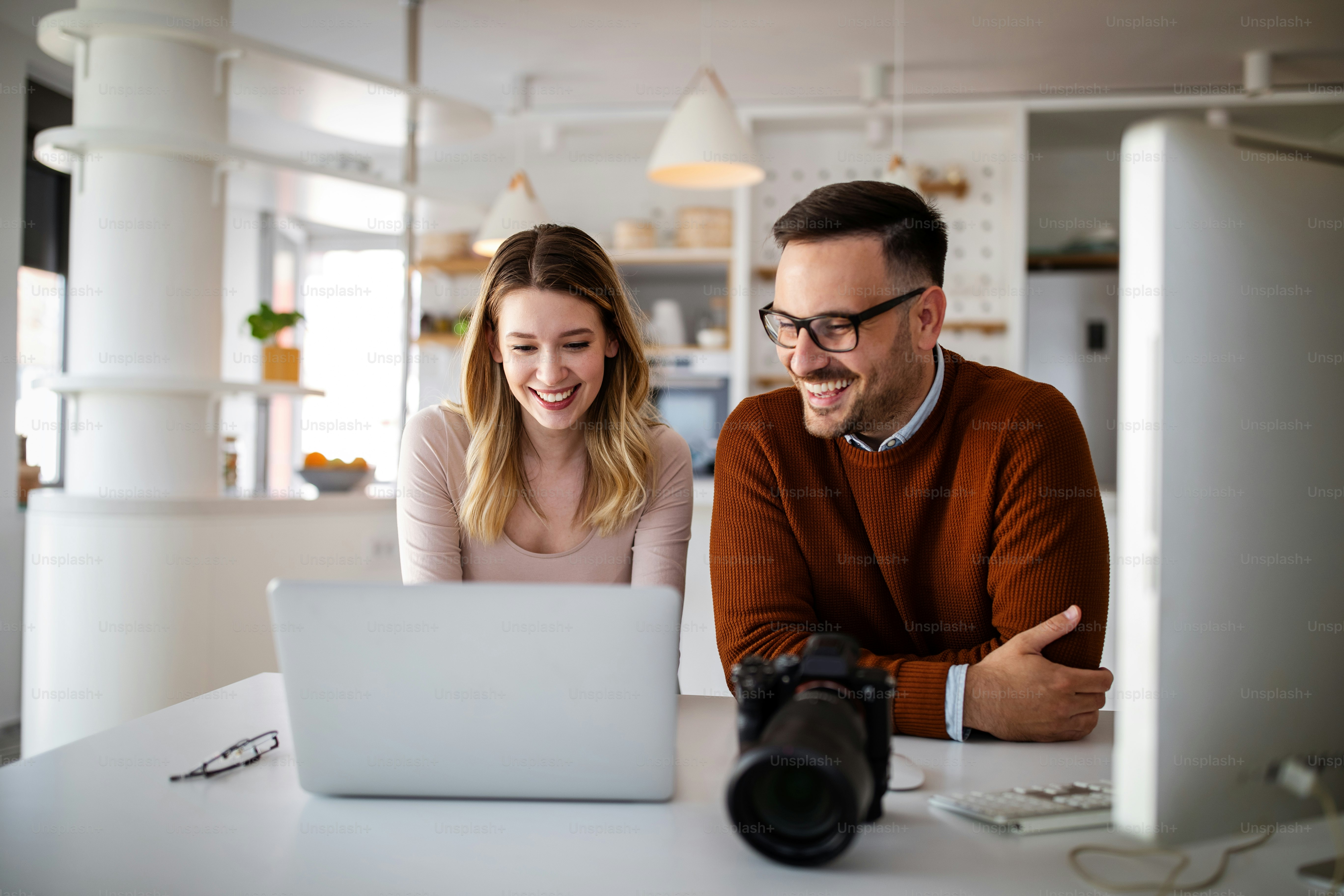 Photographer and graphic designer working in office with laptop. Creative team discussing ideas in advertising agency.