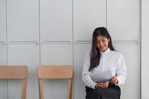Smiling woman holding resume and waiting for interview.