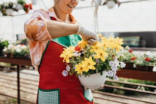 Jeune femme adulte heureuse et positive travaillant dans une serre et profitant de belles fleurs.
