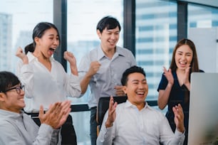 El grupo milenario de jóvenes empresarios de Asia el hombre y la mujer de negocios celebran dar cinco después de tratar sintiéndose feliz y firmando un contrato o acuerdo en la sala de reuniones en una pequeña oficina moderna.