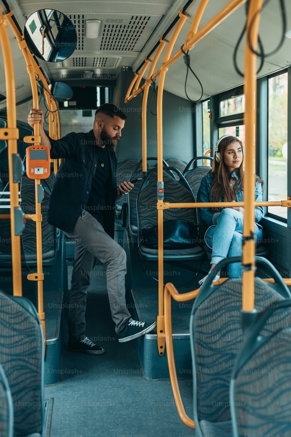 Giovani bei passeggeri che usano gli smartphone mentre guidano l'autobus durante il giorno in città