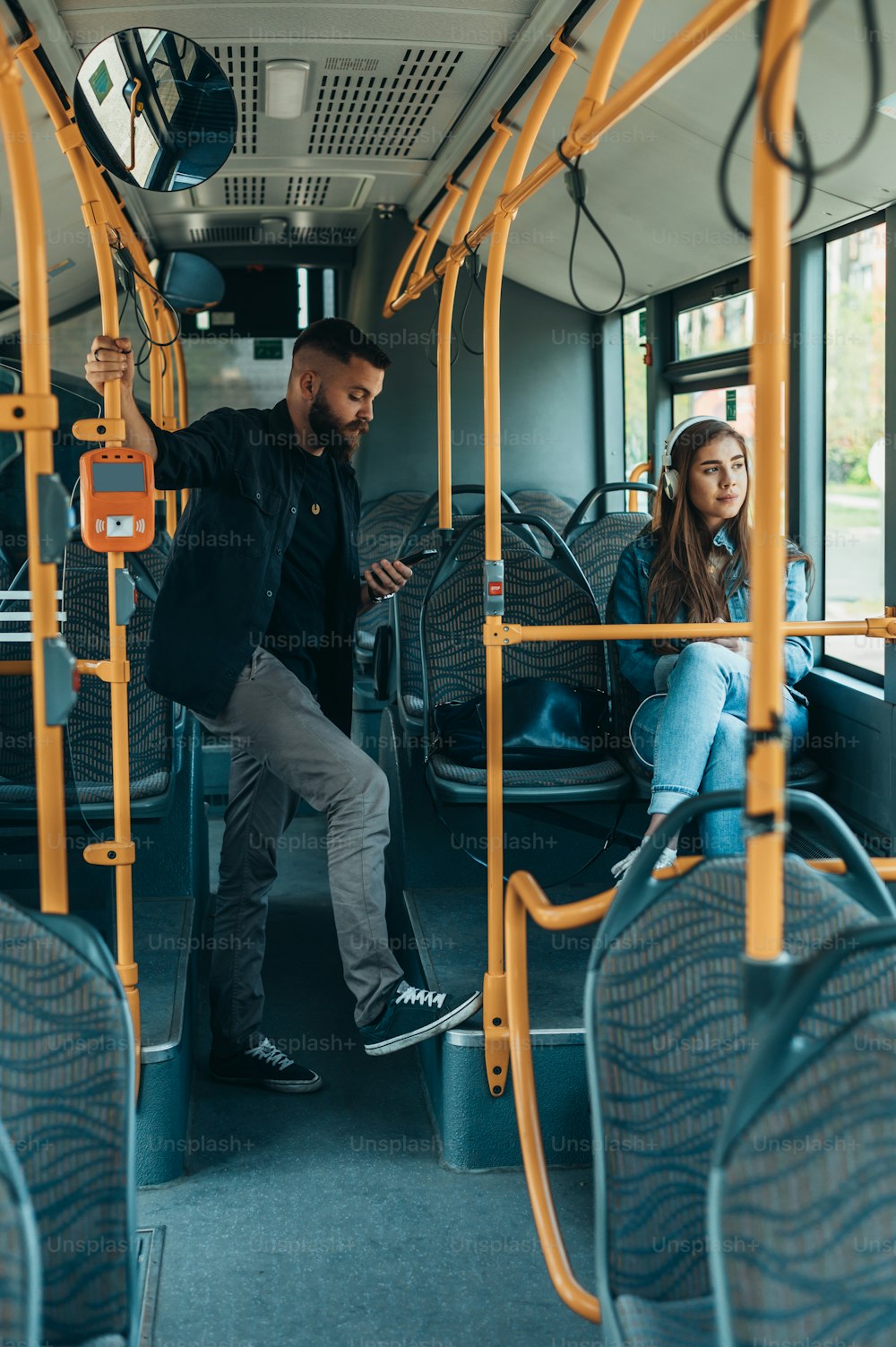 Young beautiful passengers using smartphones while riding the bus during the day in the city