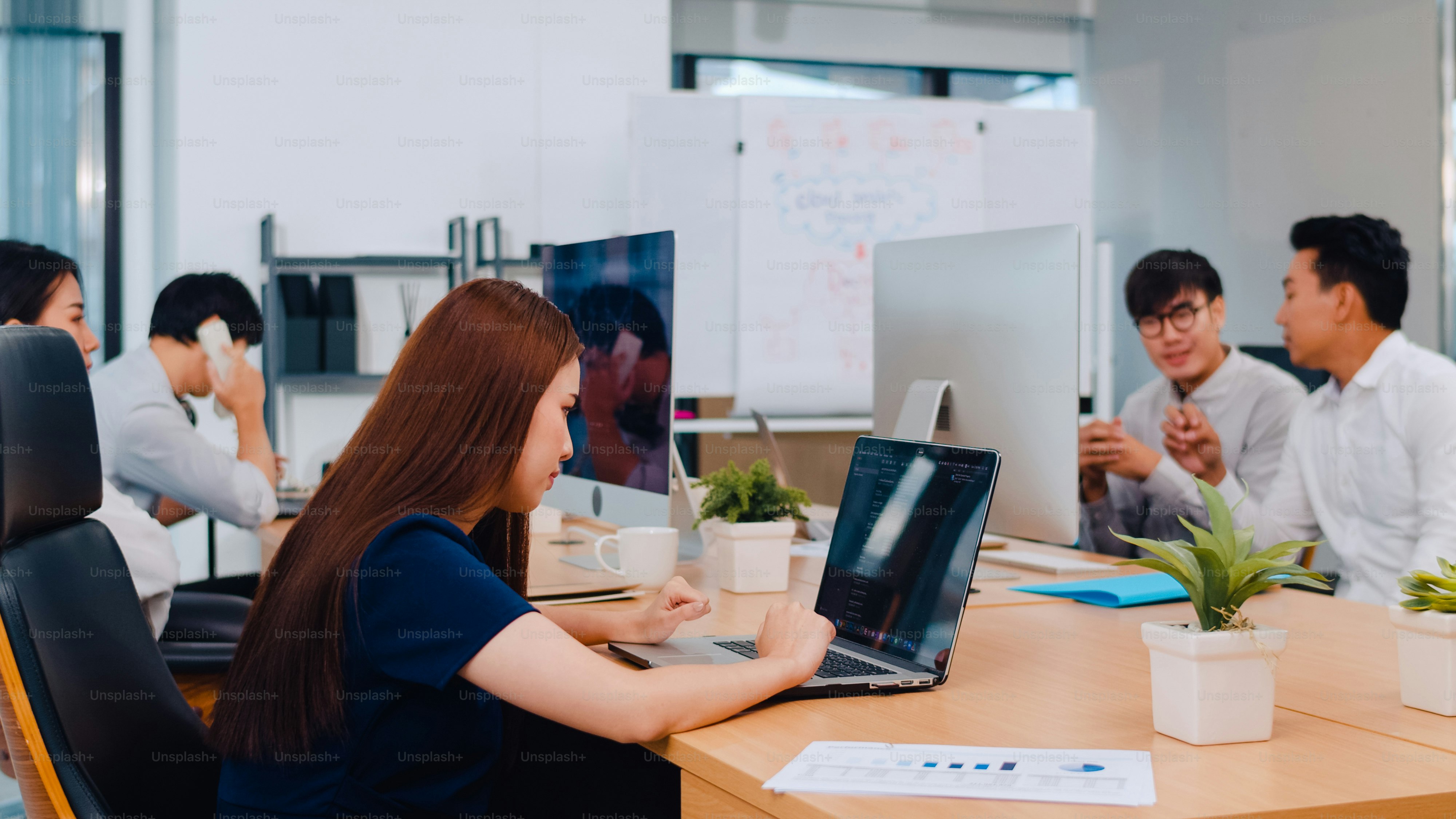 Collaborative process group of multicultural business people in smart casual wear communicating and using technology while working together in creative office. Asia team of young professionals work.