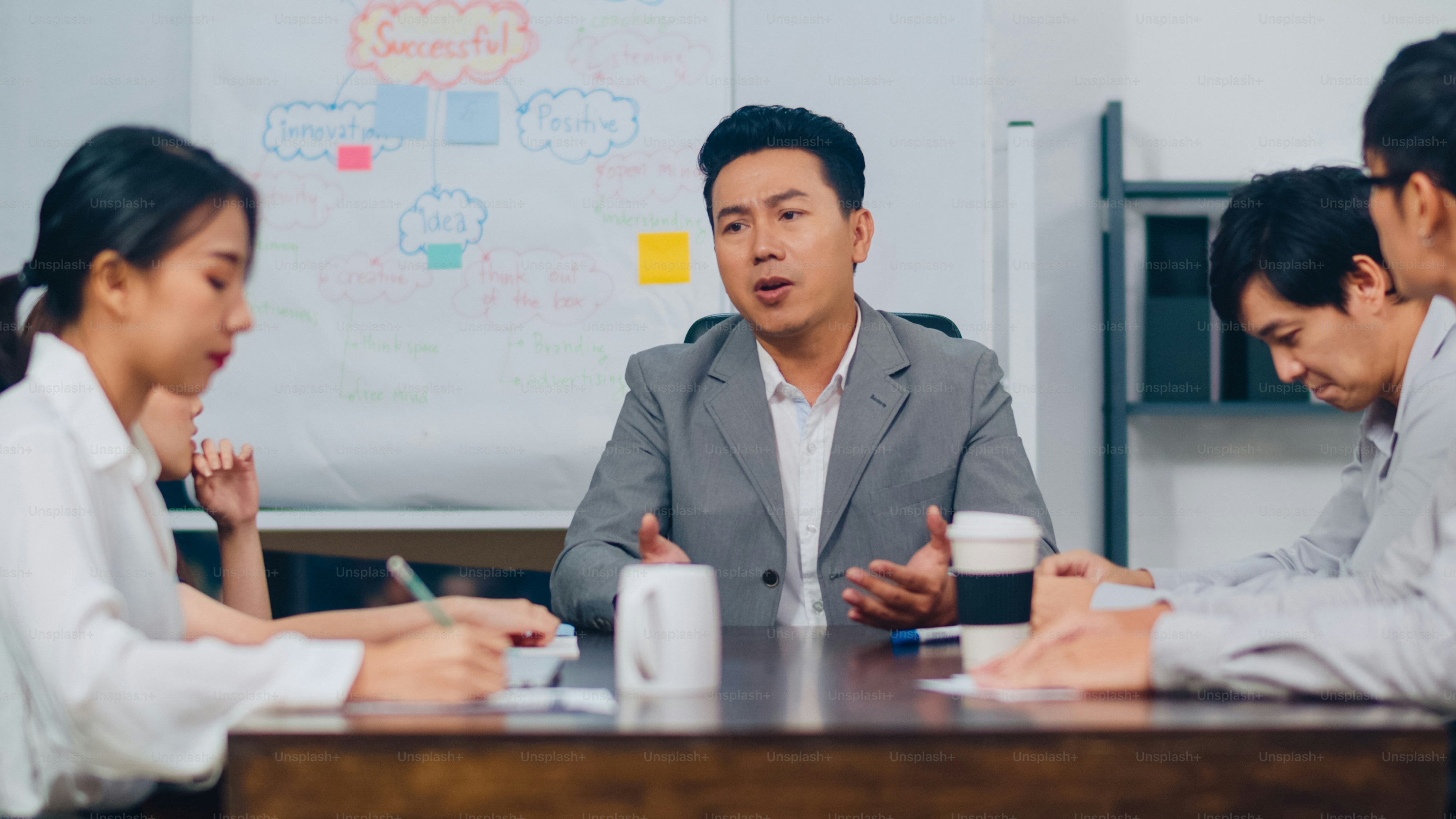 Millennial Asia businessmen and businesswomen meeting brainstorming ideas about new paperwork project colleagues working together planning success strategy enjoy teamwork in small modern night office.