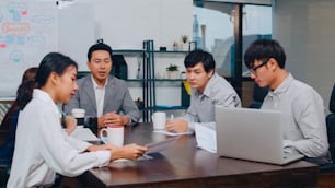 Millennial Asia businessmen and businesswomen meeting brainstorming ideas about new paperwork project colleagues working together planning success strategy enjoy teamwork in small modern night office.