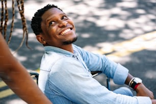 An african american man in a wheelchair enjoying a walk outdoors with his girlfriend.