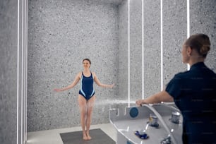 Full-length portrait of a smiling patient standing on a non-slip mat in a spa salon