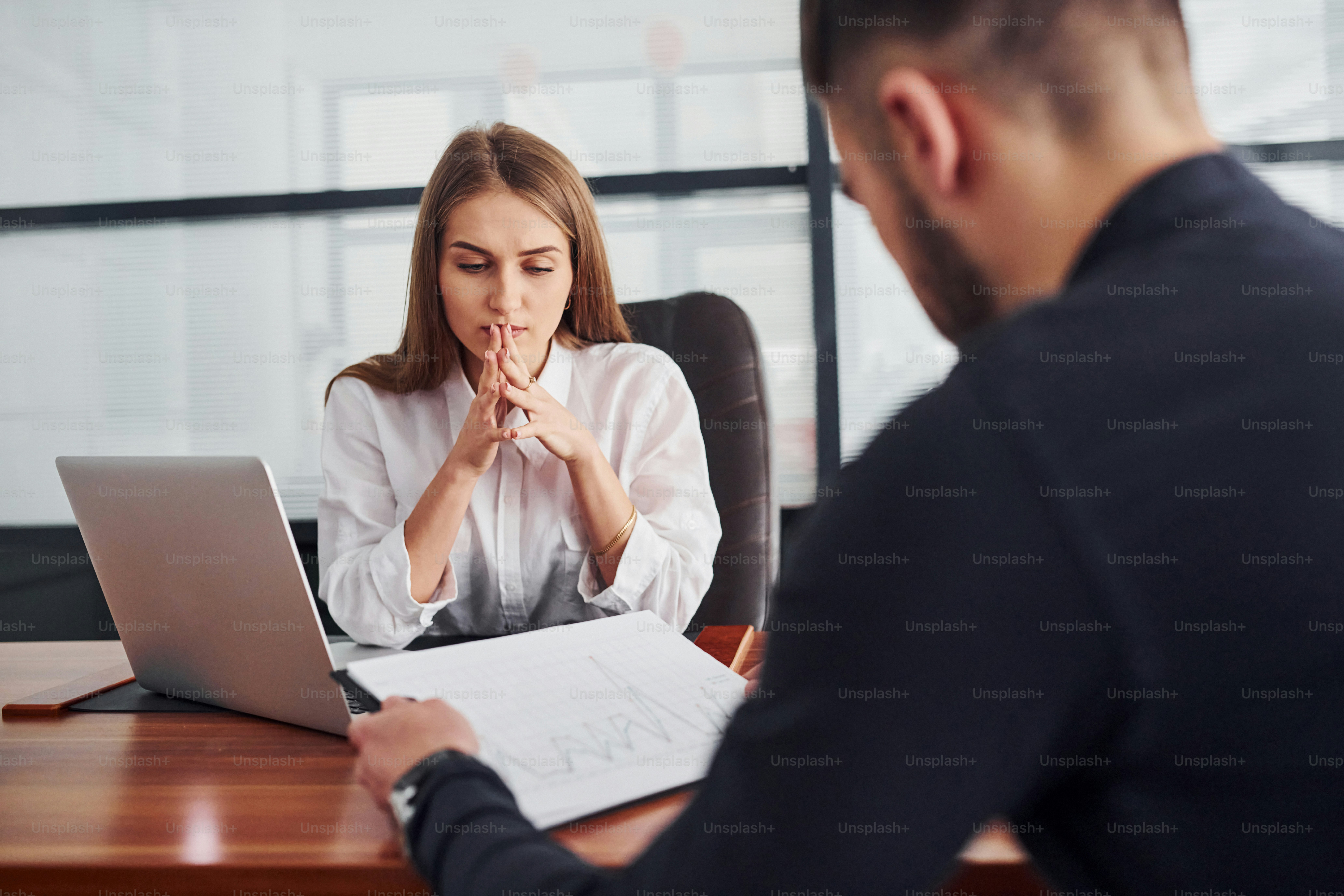 Woman and man in formal clothes working together indoors in the office by table with documents