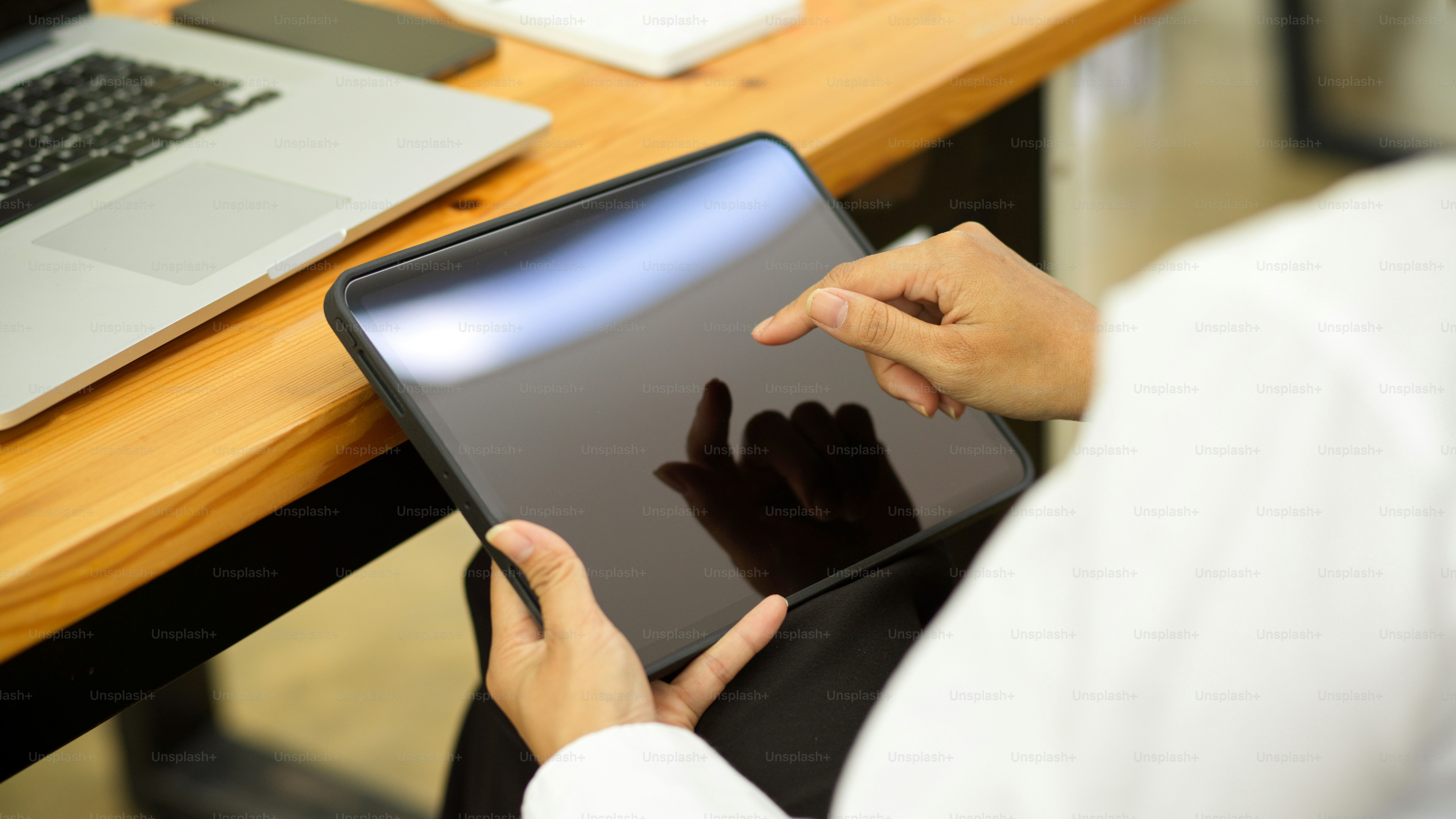 Vista laterale della mano della donna d'affari che utilizza la tavoletta digitale mentre è seduta allo spazio di lavoro