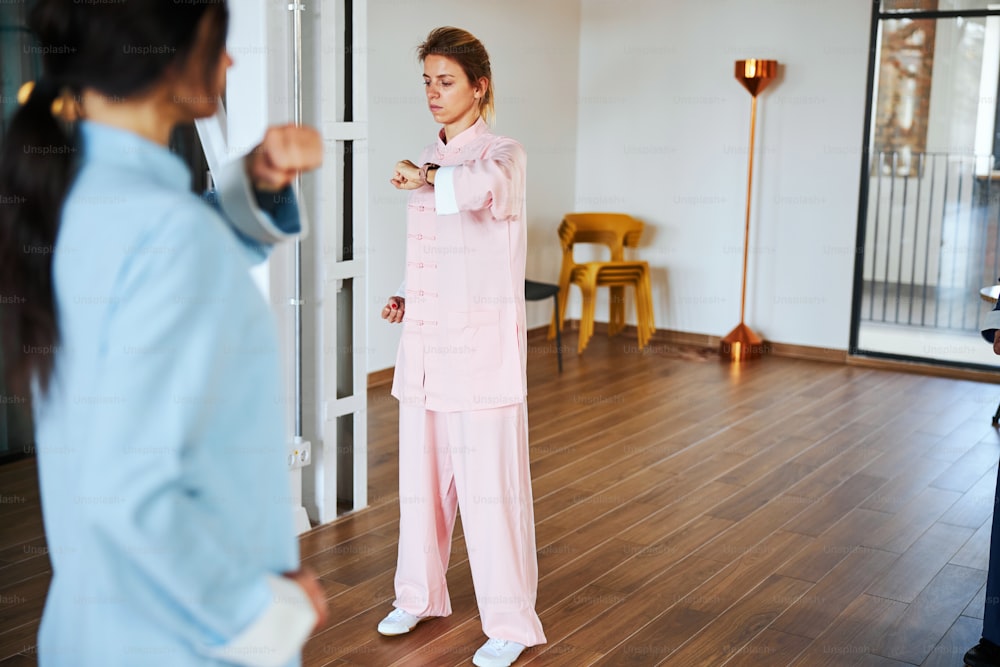 Concentrated people standing in the room and looking calm while making slow movements in their qigong practice